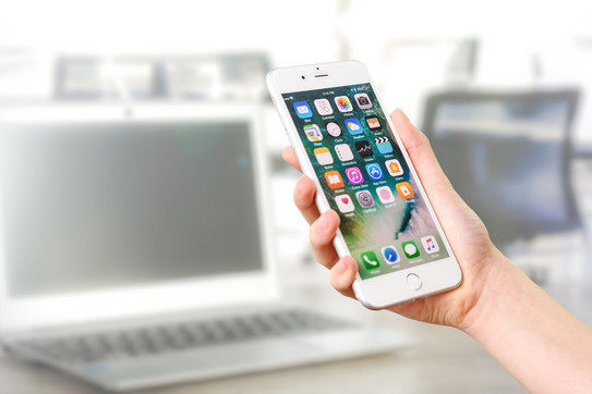 Frau hält ein Smartphone im Hintergrund sind Computer zu sehen