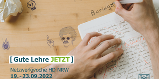 Foto: Ein bekritzelter Schultisch mit einer korrigierten Arbeit. Am Tisch sitzt eine Person, von der nur die Hände zu sehen sind, und diese schreibt das Wort "boring" auf die Tischplatte
