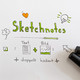 Foto: Ein Blatt Papier mit dem handgeschriebenen Wort "Sketchnotes" mittig im oberen Bereich. Darunter Zeichnungen: ein Stift mit einer Linie, darunter das Wort "Text" mit einem Blatt mit angedeuteter Schrift, rechts daneben ein Pluszeichen, rechts daneben eine Zeichnung mit einer Landschaft, über der das Wort "Bild" geschrieben steht. Darunter steht "doppelt kodiert" mit jeweils einem Stern rechts und links. Rundherum verschiedene Zeichnungen: oben links ein Herz, oben rechts eine Glühbirne, auf der linken Seite eine Denkwolke mit einem Fragezeichen darin und ein Kästchen mit einem Haken. An der unteren rechten Seite ein Pfeil, neben dem der obere Teil von zwei Moderationsstiften ins Bild ragt.