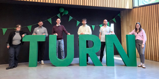 Gruppenfoto: Personen stehen hinter großen Buchstaben, die das Wort TURN bilden