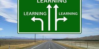 Grünes Wegweiserschild über einer Straße mit Richtungshinweisen, an denen jeweils Learning steht