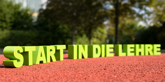 Schriftzug „Start in die Lehre“ auf einer Tartanbahn