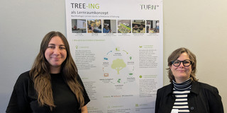 Foto: Kim Hebben und Katrin Stolz vor dem Poster zum Projekt TREE-ING